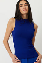 Model showcasing the Lapis Blue Gisela Sleeveless Mock Neck Top, emphasizing its high neck and pointelle detailing for a slimming look.