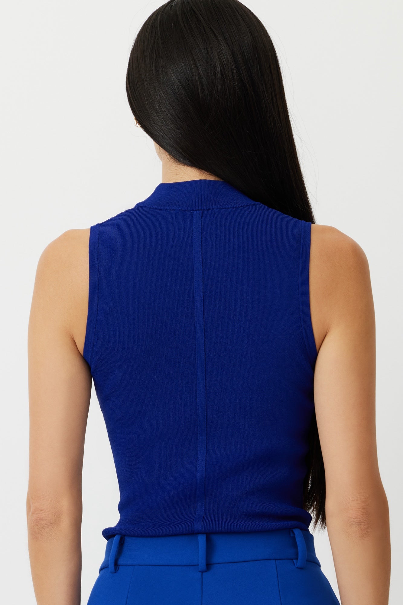 Model showcasing the Lapis Blue Gisela Sleeveless Mock Neck Top, emphasizing its high neck and pointelle detailing for a slimming look.