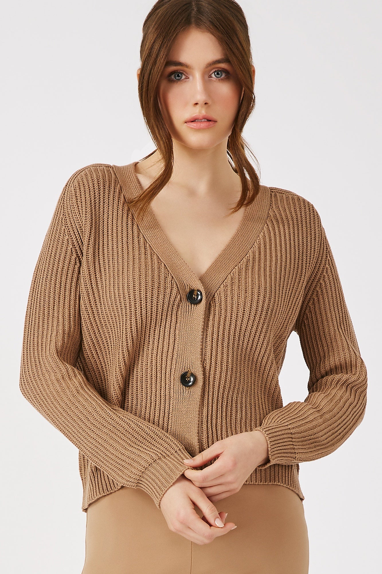 Model wearing THE OLIPHANT CARDIGAN in Desert Tan, showcasing its ribbed texture and natural horn buttons for a refined spring look.
